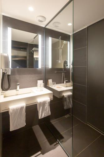 a bathroom with two sinks and two mirrors at Lorraine Hôtel Nancy Ouest - Laxou in Nancy