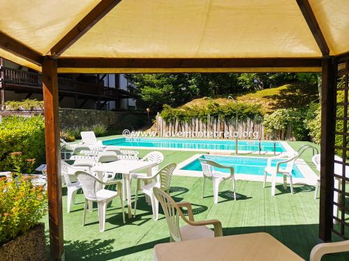 Un grupo de mesas y sillas junto a una piscina. en GranChalet sul Cimone 212, en Montecreto