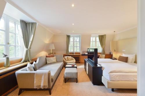 a large bedroom with a bed and a couch at Hotel Landhaus Wachtelhof in Rotenburg an der Wümme