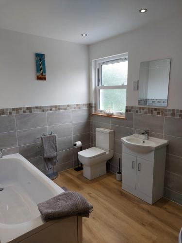 a bathroom with a tub and a sink and a toilet at Two bedroom cottage - country lane -10 min walk to Perranporth beach in Perranporth