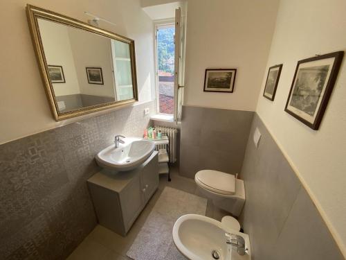Un baño con lavabo, inodoro y espejo. en Casa del lago, en Menaggio