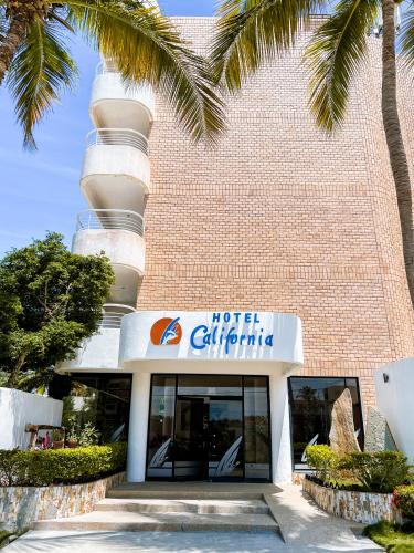 a hotel exterior with palm trees in front of a building at Hotel California Playa El Yaque in El Yaque