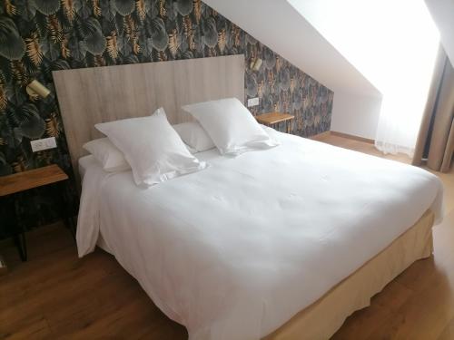 1 cama grande con sábanas y almohadas blancas en Hôtel Catalpa en Annecy