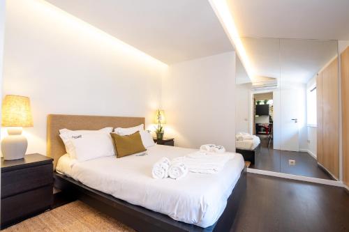 a bedroom with a large white bed with towels on it at PortugalActive Beach Flat in Viana do Castelo