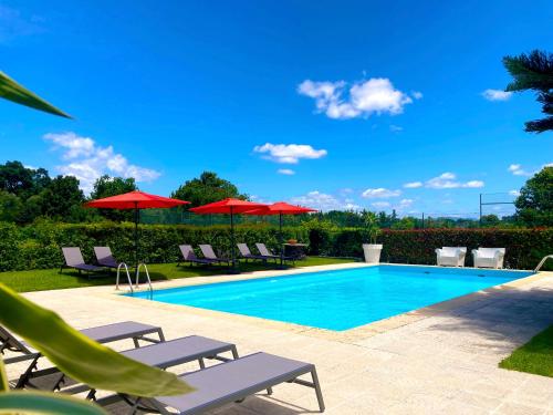 a swimming pool with chairs and red umbrellas at Quinta Dom Sapo - Agroturismo in Viana do Castelo