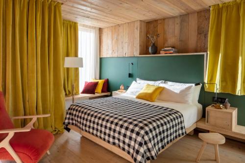um quarto com uma cama com uma parede verde e cortinas amarelas em HOTEL de LEN em Cortina dʼAmpezzo