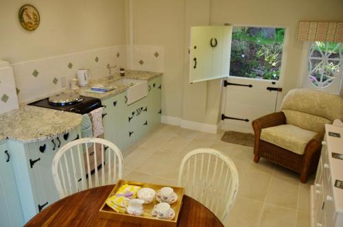 cocina con armarios blancos, mesa y sillas en The Georgian Coach House:New Forest with hot tub, en Fordingbridge
