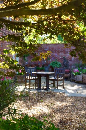 a picnic table and two chairs in a garden at The Georgian Coach House:New Forest with hot tub in Fordingbridge