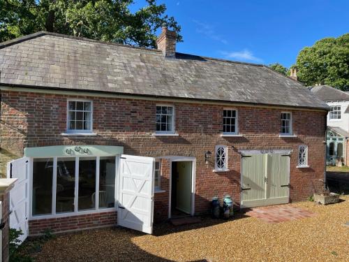 una antigua casa de ladrillo rojo con puertas blancas en The Georgian Coach House:New Forest with hot tub, en Fordingbridge