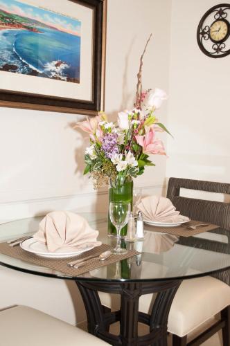 a dining room table with a vase of flowers at Laguna Shores Studio Suites in Laguna Beach