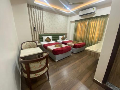 a hotel room with two beds and a couch at Hotel Sagar in Guwahati