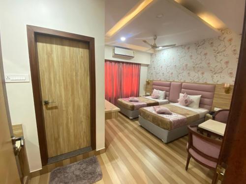 a room with two beds and a couch and a door at Hotel Sagar in Guwahati
