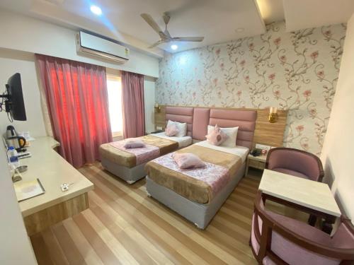 a hotel room with two beds and a couch at Hotel Sagar in Guwahati