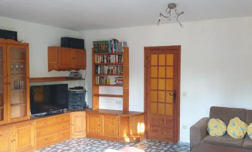 a living room with a tv and a book shelf at Casa con Encanto Mitos in Pelayos del Arroyo