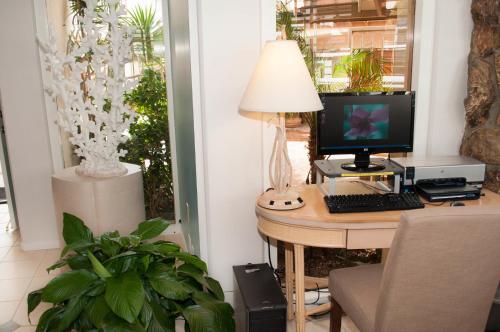 a desk with a computer and a lamp on it at Laguna Shores Studio Suites in Laguna Beach