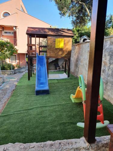 a playground with a slide on the grass at Apartmani Blaslov in Kali