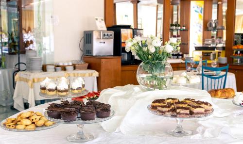 een tafel met drie borden gebak en gebak bij Hotel Ancora in Rimini