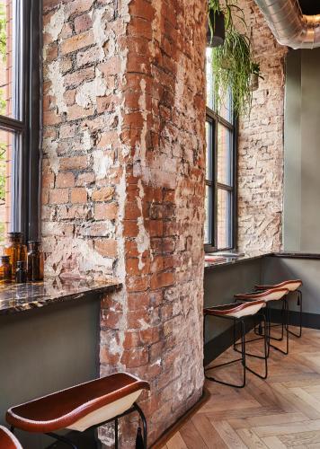 a brick wall in a restaurant with stools at Leven Manchester in Manchester