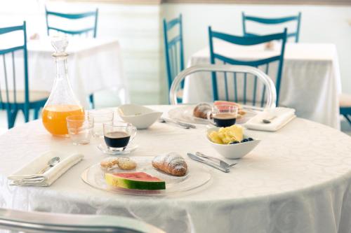 een witte tafel met een bord eten en drinken bij Hotel Ancora in Rimini
