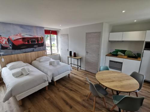 a bedroom with two beds and a table and a kitchen at Malicorn' Appart-Hôtel in Malicorne-sur-Sarthe