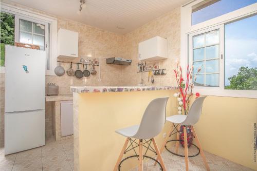 una cucina con bancone e due sgabelli di Appartement -La Source-Calme, a 10min plage-5min Trois Ilets a Les Trois-Îlets