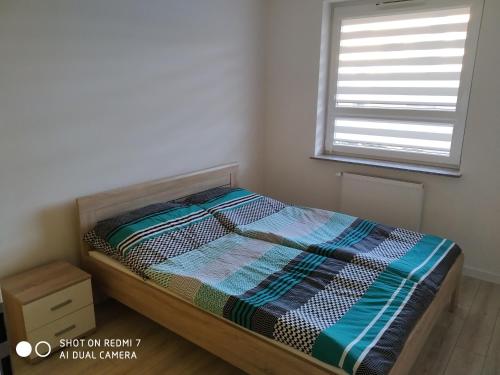 małe łóżko w pokoju z oknem w obiekcie Apartament4U - Olimpijskie Ogrody w mieście Suwałki