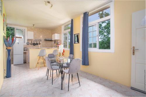 una cucina e una sala da pranzo con tavolo e sedie in vetro di Appartement La Source -Calme avec belle vue mer a Les Trois-Îlets