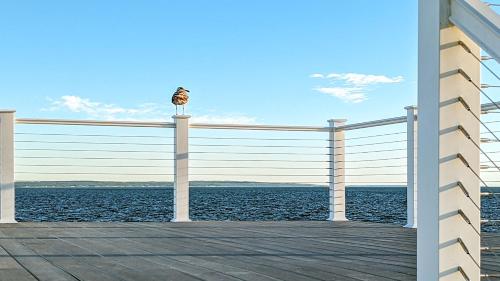 a bird sitting on a pole on a pier near the water at Falmouth Tides in Falmouth