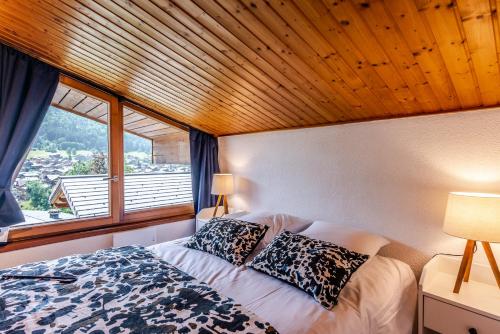 une chambre avec un lit et une grande fenêtre dans l'établissement POLATON 3, à Morzine