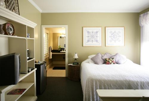 a bedroom with a white bed and a television at West Kauai Lodging in Waimea