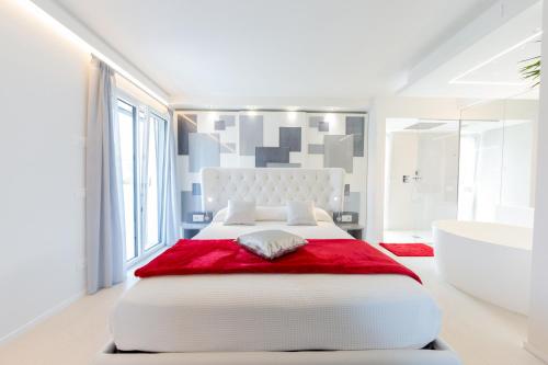 a white bedroom with a large white bed and a tub at Magic Luxury Apartments in Bardolino