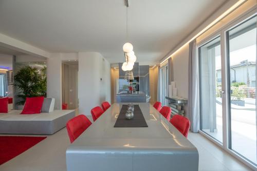 a dining room with a long table and red chairs at Magic Luxury Apartments in Bardolino
