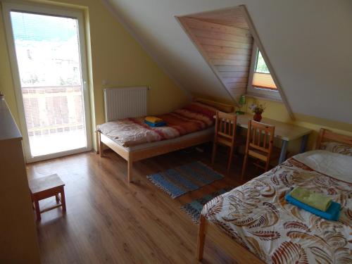 1 dormitorio en el ático con 2 camas, mesa y sillas en Sunny Holiday House B&B, en Ljubno