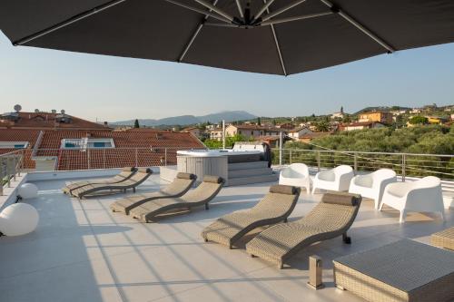 a group of chairs and an umbrella on a roof at Magic Luxury Apartments in Bardolino