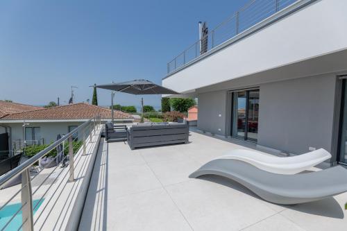 a balcony with a white bench and an umbrella at Magic Luxury Apartments in Bardolino