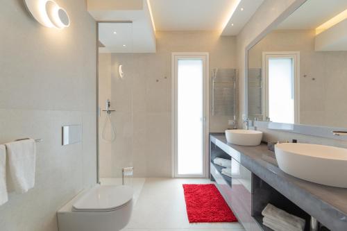 a bathroom with two sinks and a red rug at Magic Luxury Apartments in Bardolino