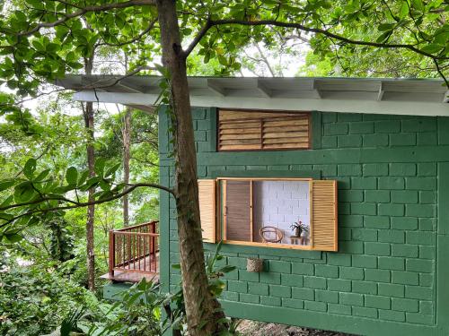 a green brick building with a window and a balcony at Casa Galú - Capurganá in Capurganá
