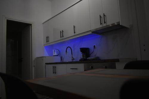 a kitchen with white cabinets and a blue light at George & Dimitra's House in Kharokopión