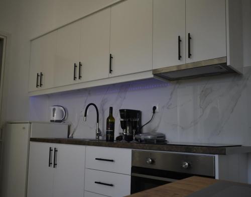 a kitchen with white cabinets and a sink at George & Dimitra's House in Kharokopión
