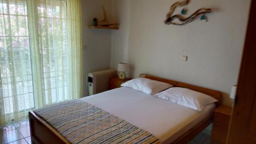 a bedroom with a bed with white sheets and a window at Palm Villa in Astris