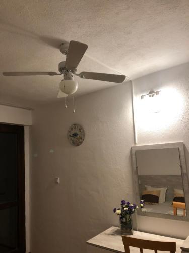 Habitación con ventilador de techo y espejo. en Family Hotel Southern Nights en Varvara