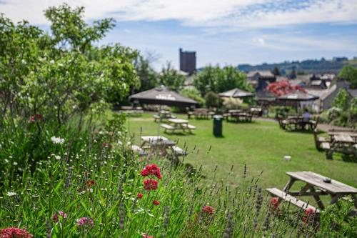 a park with picnic tables and flowers in the grass at The Castle Of Brecon Hotel, Brecon, Powys in Brecon