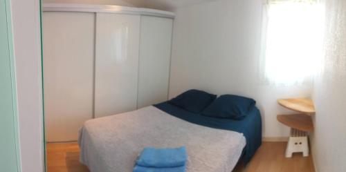 1 dormitorio con cama con sábanas azules y ventana en AIGUES-MORTES - AGRÉABLE T.2 - (+ de 40m² ), en Aigues-Mortes