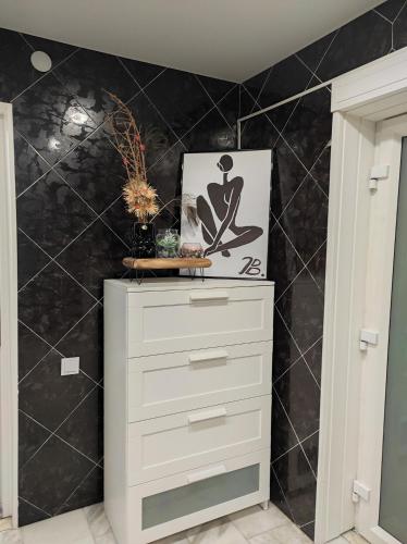 a white dresser in a room with a black wall at Vila su sauna ir kubilu gamtos apsuptyje in Kalviškiai