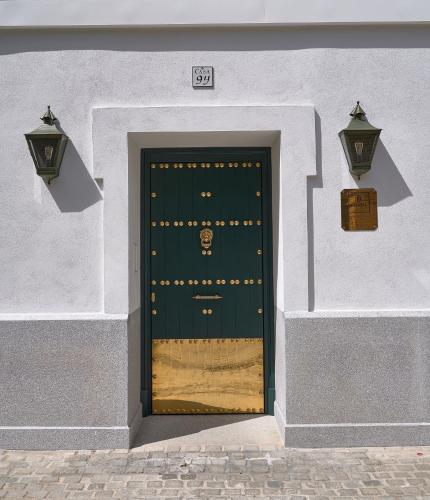 a green door in a white building with two lights at Hotel Boutique Triana House in Seville