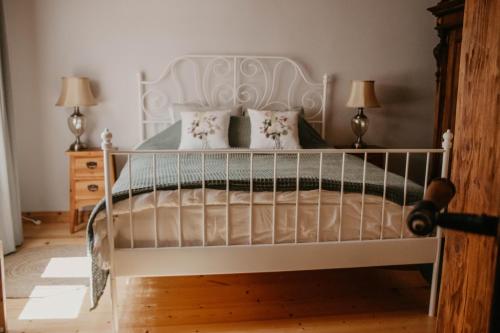 a bedroom with a white bed with two lamps at Zelta Apelsīna apartamenti in Kuldīga