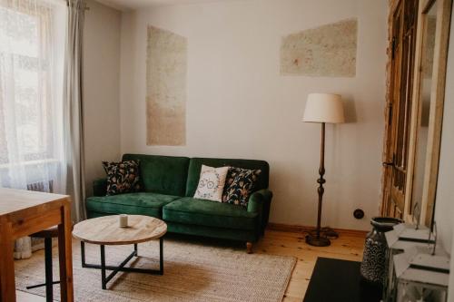 a living room with a green couch and a table at Zelta Apelsīna apartamenti in Kuldīga