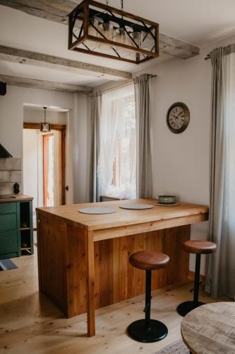 a kitchen with a wooden island with two bar stools at Zelta Apelsīna apartamenti in Kuldīga