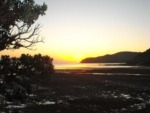 a sunset on the beach with the sun setting at Tipi and Bobs Waterfront Lodge in Tryphena