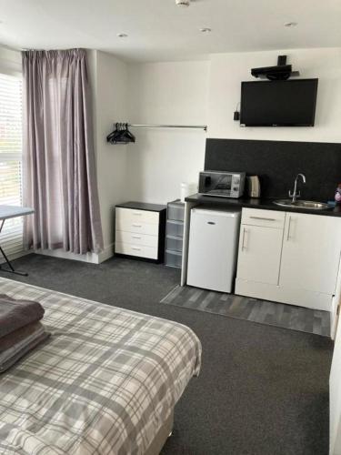 a room with a bed and a kitchen with a sink at The Gladson Guesthouse in Cleethorpes